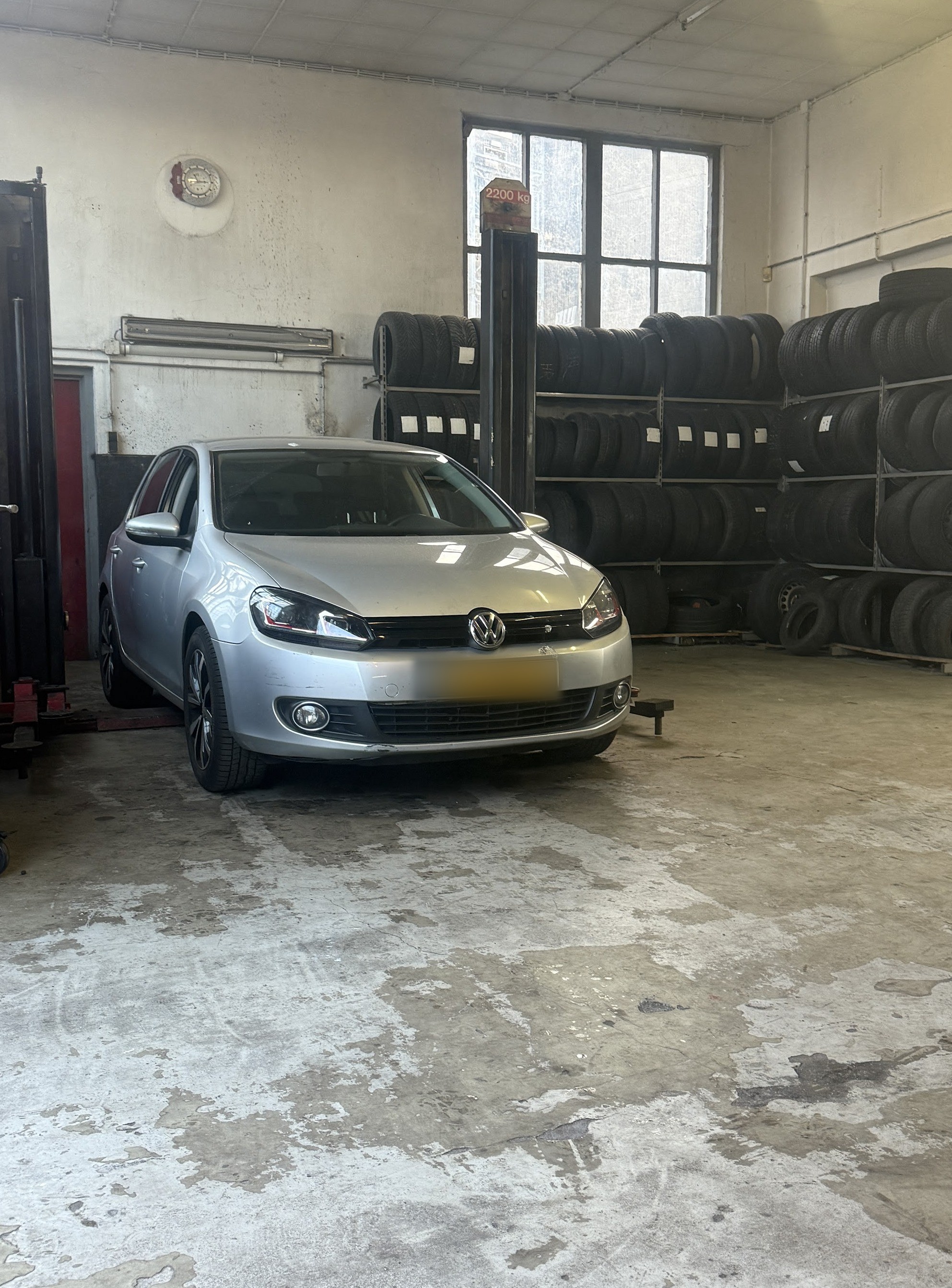 Zilveren Volkswagen Golf in de werkplaats, met banden op de achtergrond