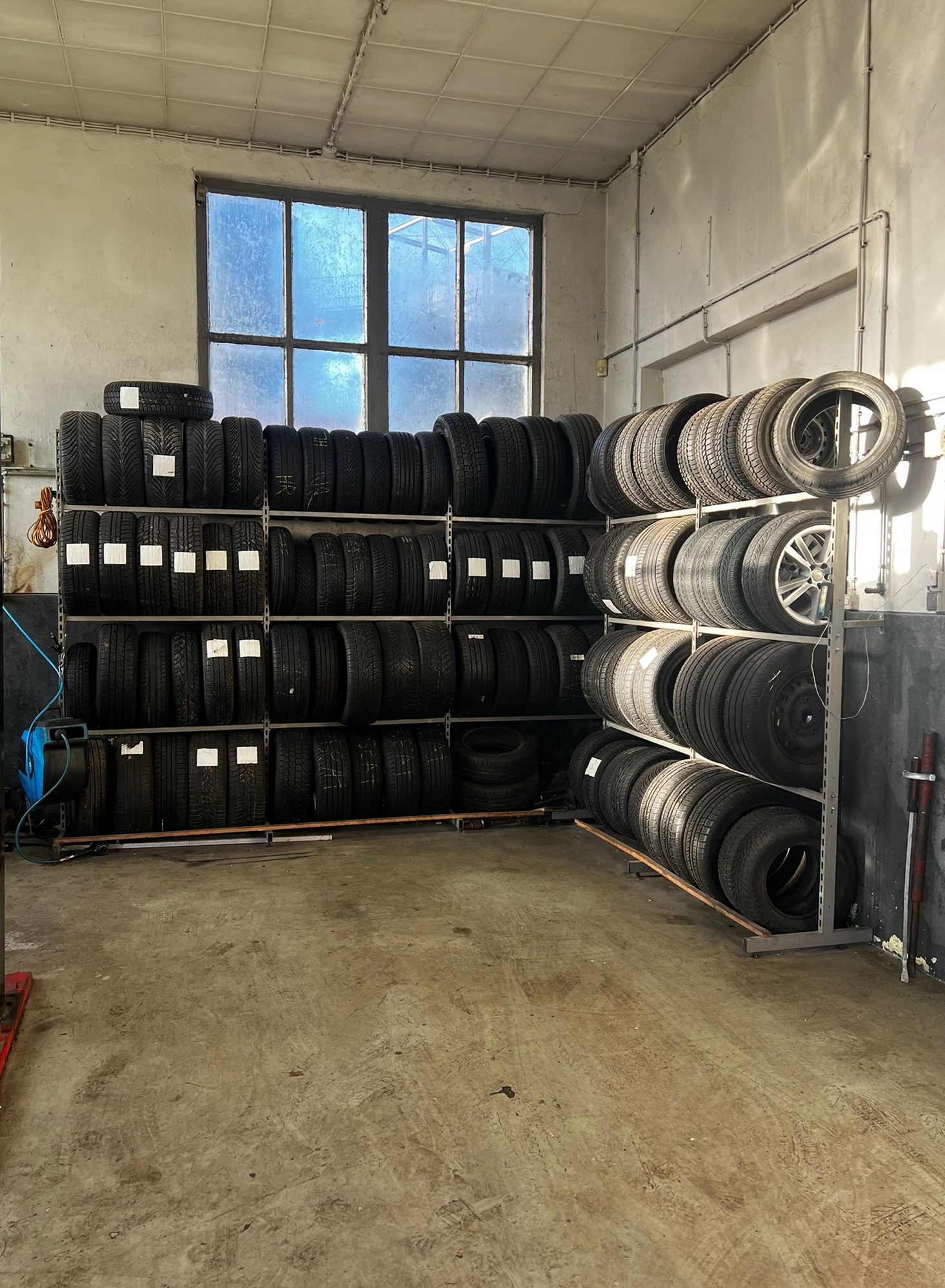 Rekken met nieuwe en gebruikte banden langs de muur van de werkplaats