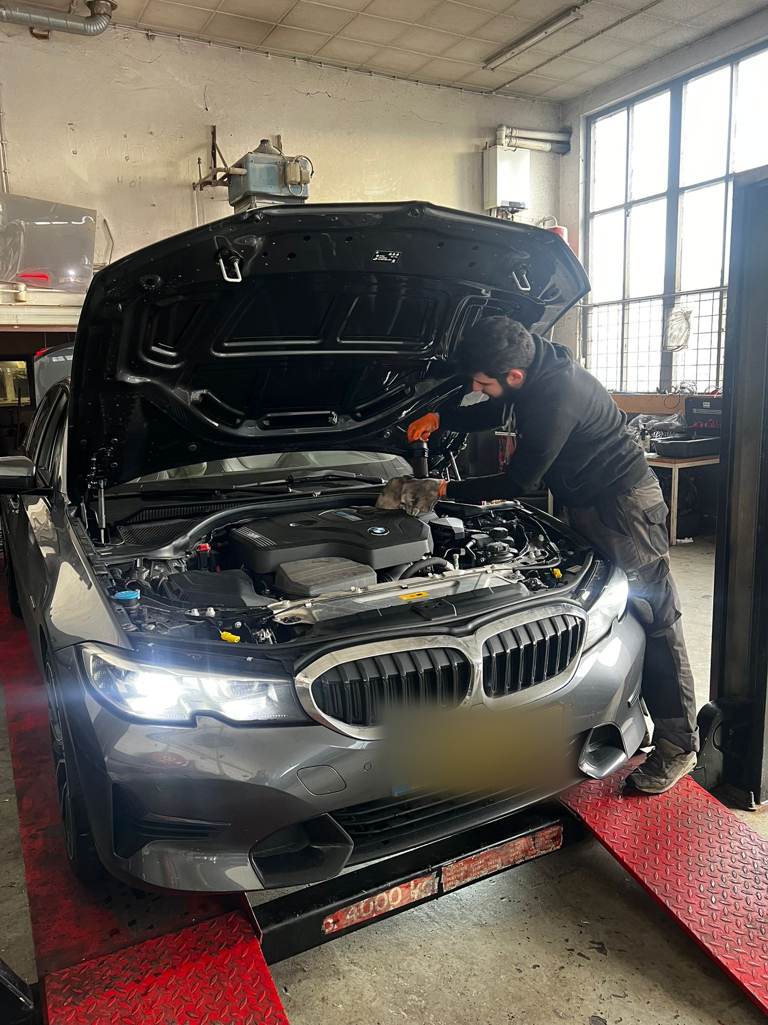 Monteur aan het werk onder de motorkap van een BMW op de brug